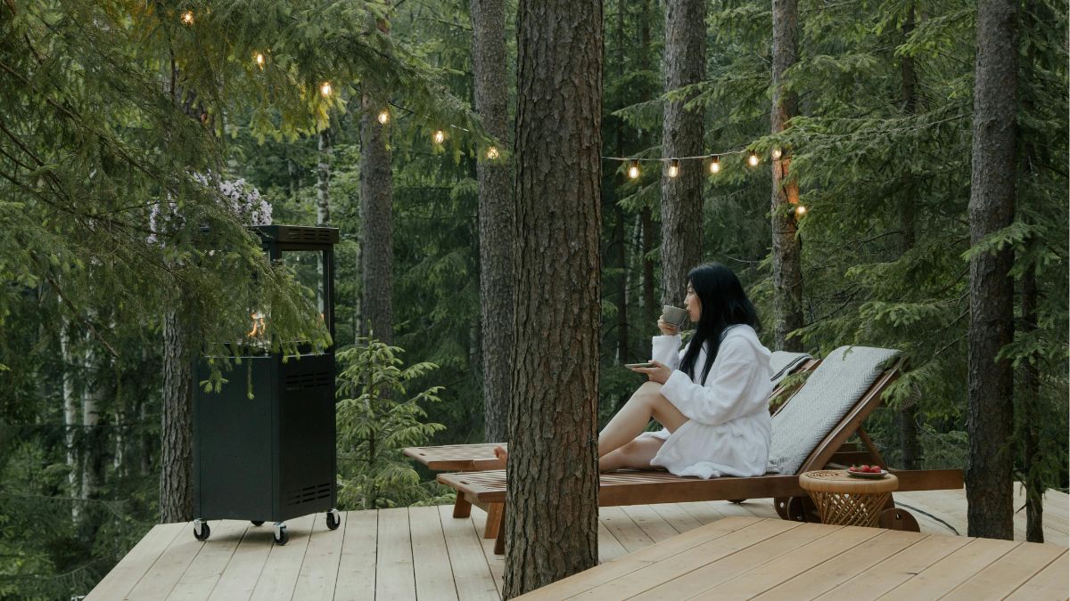 Woman in Bathrobe Sitting on a Lounge Chair while Drinking Beverage